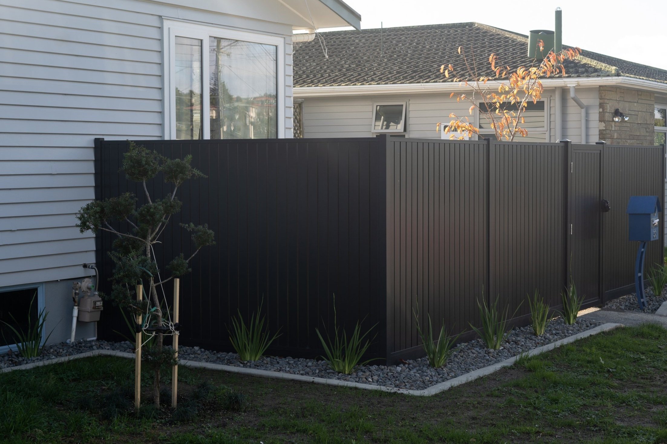 Classic vertical slat wooden fence with greenery.